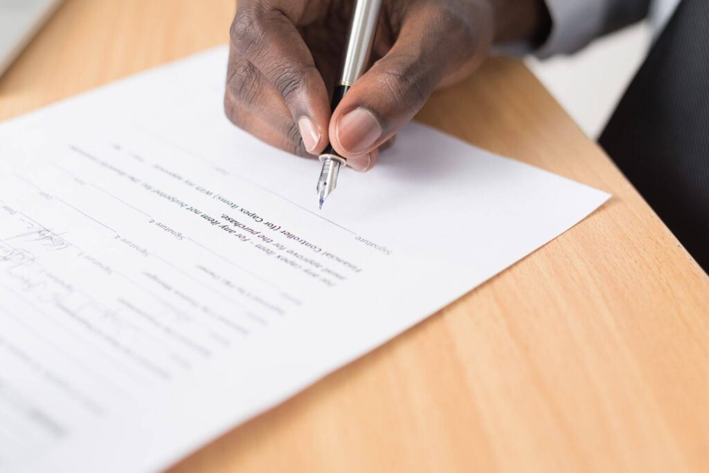 Person filling out a document with a pen