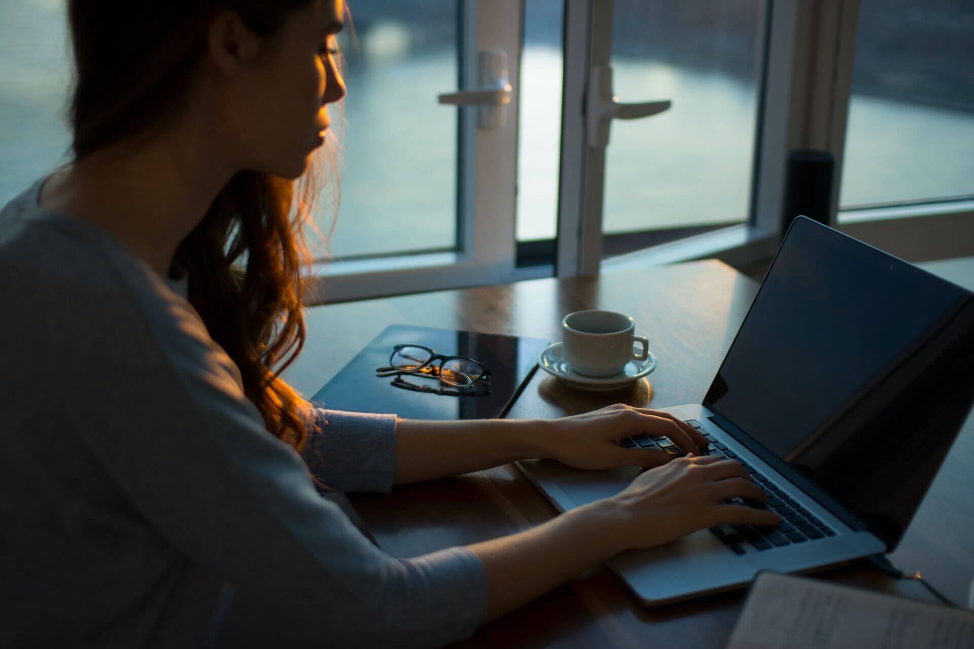 A woman working on a laptop in the evening.