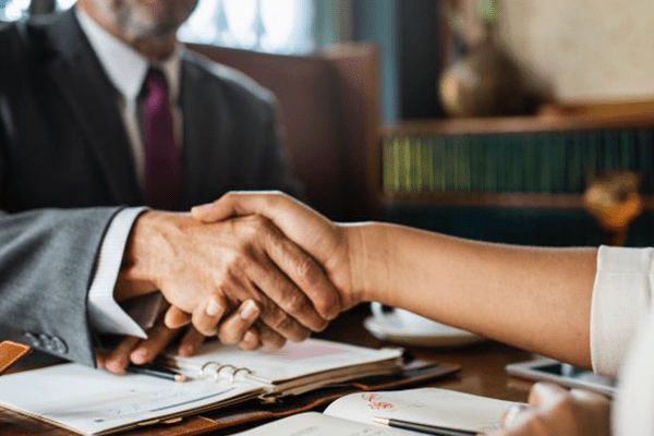 A lawyer shaking hands with their client after winning a settlement.