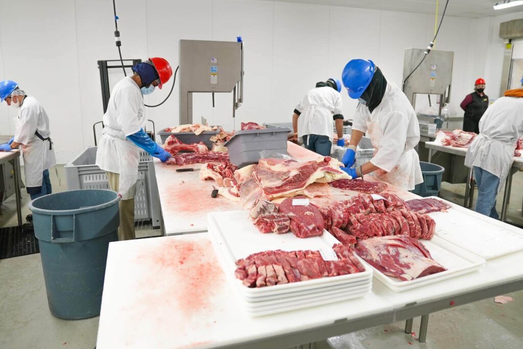 A group of workers in the food industry cutting meat
